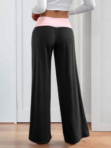 Detail view of pink fold-over waistband and black wide-leg yoga pants from behind