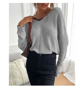 Detailed close-up of grey V-neck knit sweater with elegant black lace stitching detail