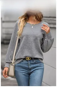 Close-up of gray long sleeve knit top featuring unique geometric textured fabric pattern
