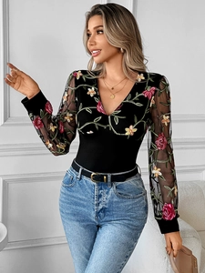 Detail of elegant black V-neck top featuring floral embroidery on sheer mesh sleeves
