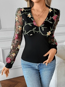 Detail of elegant floral embroidery and translucent lace mesh sleeves on the V-neck top