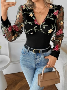Detail of black V-neck bodysuit featuring floral embroidery and sheer mesh sleeves