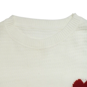 Close-up of ribbed crewneck and soft knit texture on white sweater with heart detail