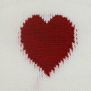 Macro shot of red knitted heart pattern on off-white sweater showing detailed fiber texture