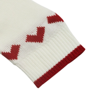 Detailed close-up of cream knit sleeve with red heart jacquard and ribbed cuff texture
