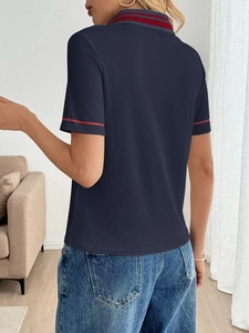 Detail view of the back of a navy ribbed knit polo shirt with striped collar and cuffs
