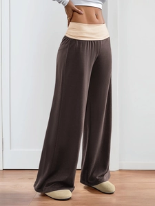 Detail of high-waist patchwork waistband and soft brown fabric on wide-leg trousers