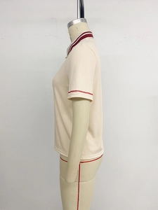 Side view of beige ribbed polo shirt featuring red stripe accents on sleeves and collar