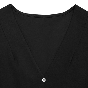Close-up of deep V-neckline on black dress with textured fabric and white button detail