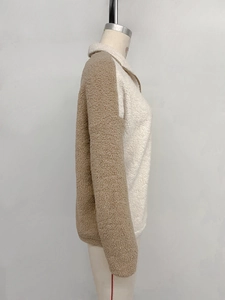 Close-up of color-block sherpa fleece texture and high-collar zipper details on sweatshirt