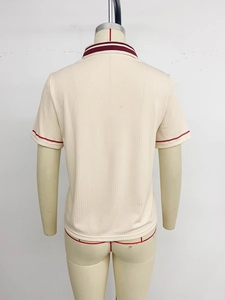 Detail of beige knit polo shirt back featuring red double stripes on sleeve and collar