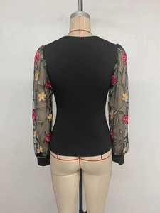 Detail of floral embroidery on sheer mesh sleeves of a black slim fit women's top