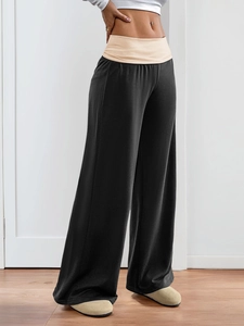 Detail of black wide-leg trousers featuring a beige fold-over high waistband design