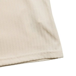 Close-up of ribbed knit texture and double-stitched hem on this cream polo shirt
