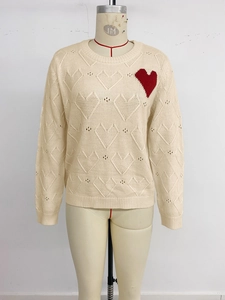 Close-up of heart jacquard pattern and red knitted heart patch on cream crewneck sweater