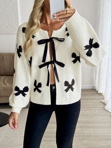Détail du cardigan en maille blanc avec motifs papillons noirs et liens en ruban