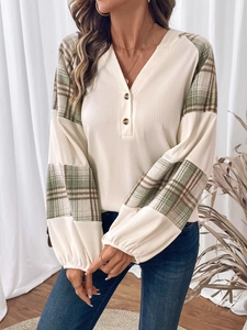 Dettaglio dello scollo a V in maglia a costine con bottoni e maniche patchwork