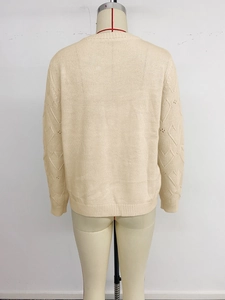 Detail view of heart jacquard pattern and hollow knit sleeves on the beige sweater