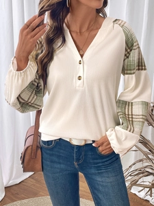 Dettaglio del tessuto a costine e maniche patchwork a quadri su maglia con scollo a V