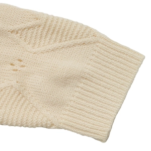 Detailed macro view of cream cable knit sweater cuff with hollow out polka dots