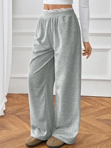 Detail of grey wide-leg trousers featuring white lace trim and elastic waistband design