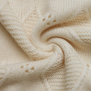 Detailed macro view of cream-white knit fabric with diamond texture and hollow-out patterns