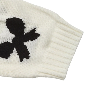 Détails des poignets côtelés et motifs floraux noirs sur un cardigan en maille crème