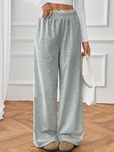 Macro detail of high-waist grey wide-leg trousers with elegant white lace waist trimming