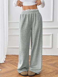 Detail of grey wide leg trousers featuring a delicate white lace waistband design