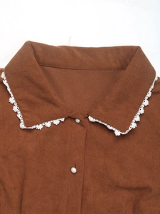 Detail of corduroy collar with delicate white lace trim and round white buttons
