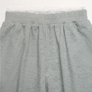 Close-up of elastic waistband with white lace trim on grey knit wide leg trousers