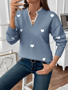 Close-up of blue V-neck knit sweater with heart pattern and white lace trim detail
