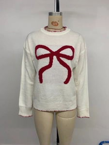 Detail of red bow jacquard pattern and contrast stitching on white knit sweater