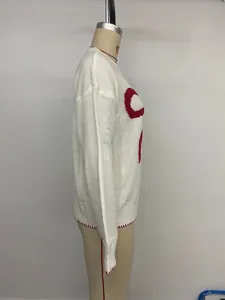 Detail view of white knitted Christmas sweater showing red jacquard pattern and stitching