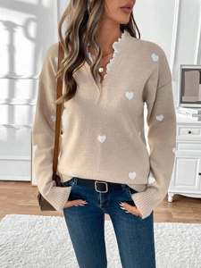 Detail of beige V-neck knit sweater with heart patterns and delicate lace trim