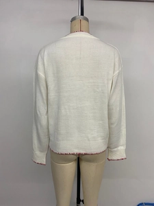 Detail of white knit sweater back showing red contrast stitching and ribbed hem