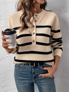 Detail of waffle knit striped sweater featuring dark wood buttons and textured beige fabric