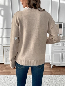 Detail view of beige knit sweater with white lace collar and heart-shaped elbow patches