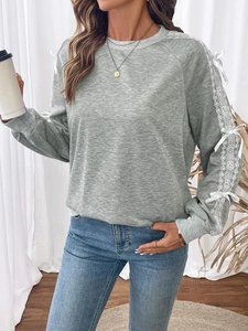Detail of grey sweatshirt with delicate white lace patchwork and bow on the sleeve