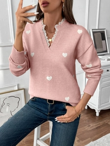 Detail of V-neck pink knit sweater with white heart pattern and delicate lace trim edges