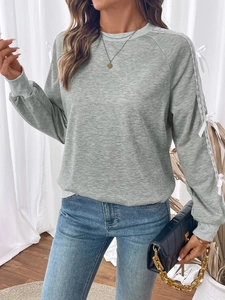 Detailed view of grey sweatshirt sleeves with white lace stitching and ribbon bow knots