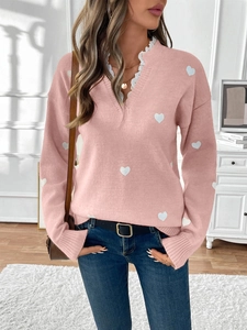 Detail of V-neckline with delicate white lace trim on pink heart pattern knit sweater