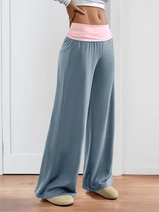 Detail view of wide-leg trousers featuring a pink fold-over waistband and soft gray fabric