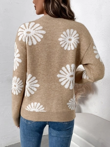 Detail des beigen Strickpullovers mit weißen Gänseblümchenmustern und Rippbündchen