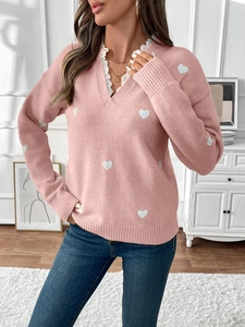 Detail of pink V-neck knit sweater featuring white lace trim and heart pattern