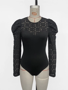 Detail of black bodysuit featuring sheer geometric lace long sleeves and puff shoulders