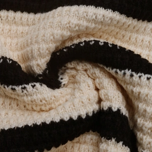 Macro close-up showing the chunky knit texture and black and white striped wool fabric