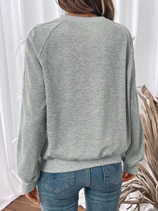 Detail of light grey raglan sleeve sweatshirt with decorative white ribbon bows on arms