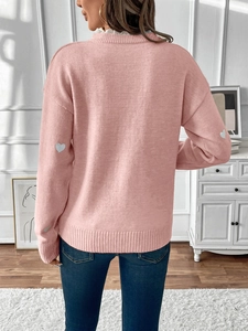 Detail shot of pink knit sweater featuring grey heart patches on the sleeves back view