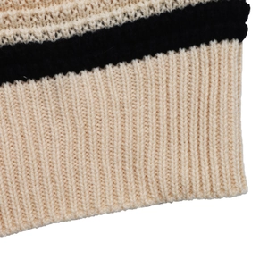 Close-up of the ribbed knit texture and black striped pattern on a cream beige sweater